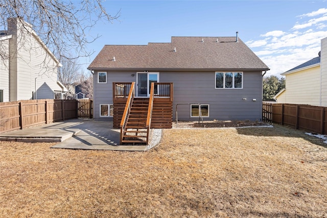 back of property with a patio area, a fenced backyard, stairway, and roof with shingles