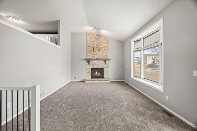 unfurnished living room with carpet, a fireplace, lofted ceiling, a textured ceiling, and baseboards