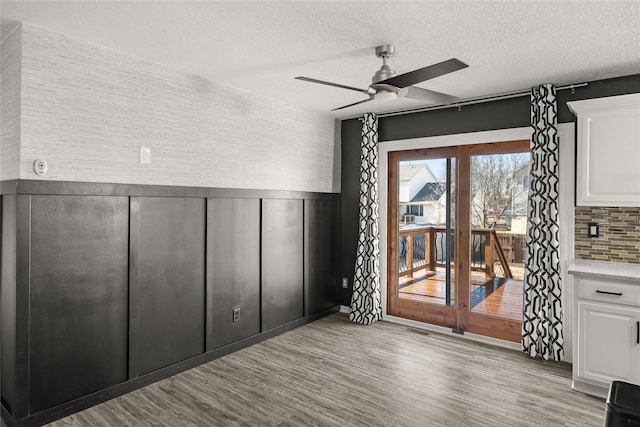 interior space with visible vents, wainscoting, wood finished floors, access to exterior, and a textured ceiling