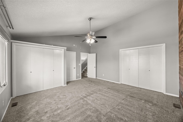 unfurnished bedroom with multiple closets, carpet, visible vents, and a textured ceiling