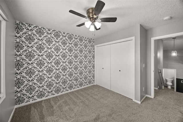 unfurnished bedroom featuring a textured ceiling, a closet, carpet flooring, and baseboards