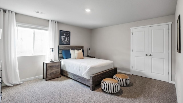 bedroom with light carpet, baseboards, visible vents, and a closet