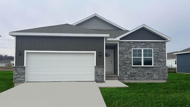 view of front facade featuring a shingled roof, an attached garage, stone siding, driveway, and a front lawn