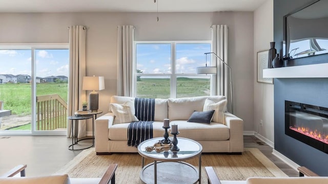 living area with a glass covered fireplace, plenty of natural light, and baseboards