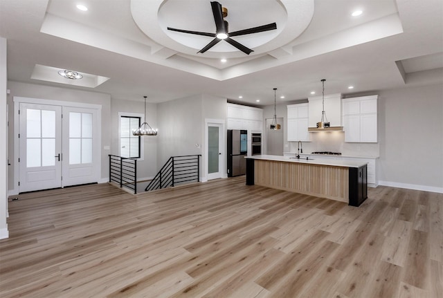 kitchen with light wood-style flooring, a raised ceiling, and light countertops