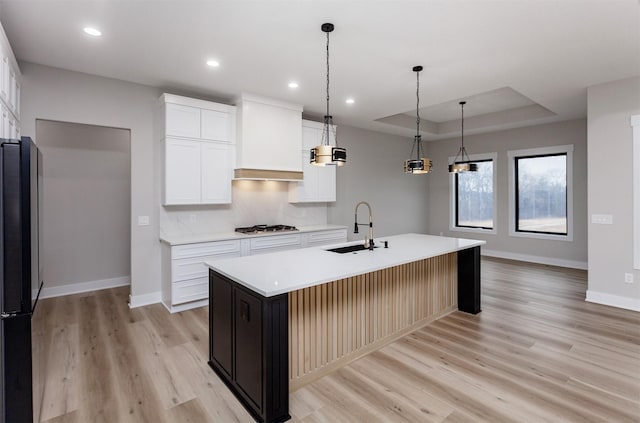 kitchen featuring stainless steel gas stovetop, a raised ceiling, a sink, and light countertops