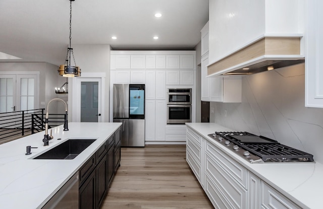 kitchen with white cabinets, custom exhaust hood, stainless steel appliances, and a sink