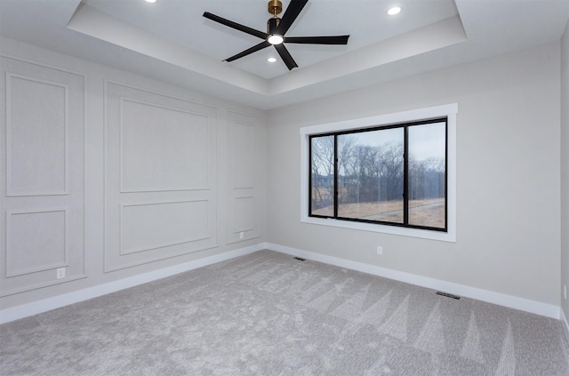 unfurnished room with carpet floors, recessed lighting, a raised ceiling, and baseboards