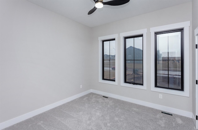 empty room with carpet floors, visible vents, baseboards, and a ceiling fan