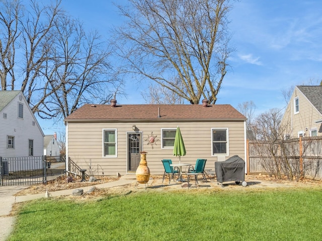 rear view of property featuring a patio area, a yard, and fence