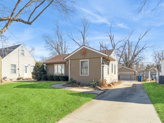 view of front of home with an outbuilding, a detached garage, roof with shingles, a gate, and a front yard