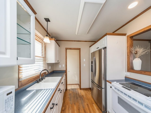 kitchen featuring decorative light fixtures, light wood-style floors, white cabinets, a sink, and white appliances