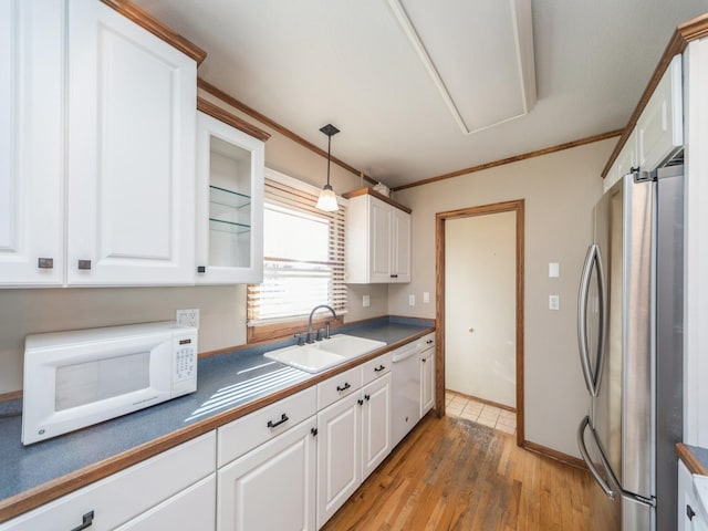 kitchen featuring dark countertops, white appliances, white cabinetry, and a sink