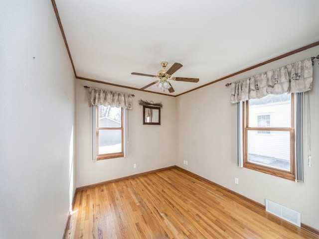 unfurnished room featuring baseboards, light wood finished floors, visible vents, and crown molding