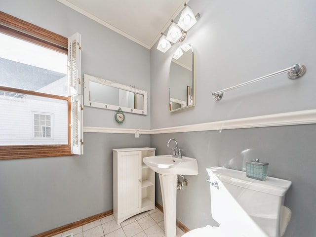 bathroom with baseboards, toilet, tile patterned flooring, crown molding, and a sink