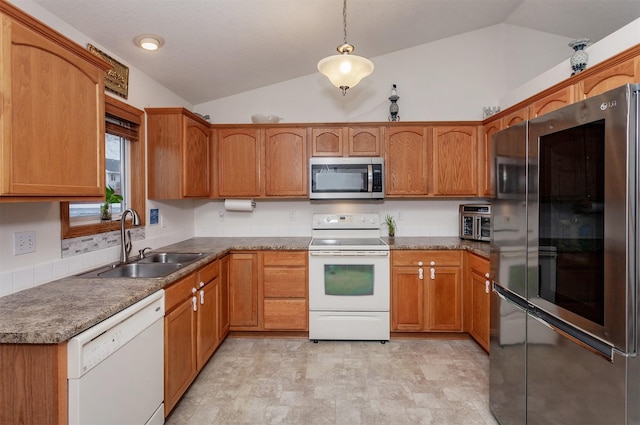 kitchen featuring vaulted ceiling, brown cabinets, appliances with stainless steel finishes, and a sink