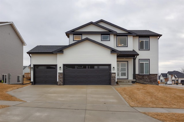 craftsman-style house with stone siding, concrete driveway, and an attached garage