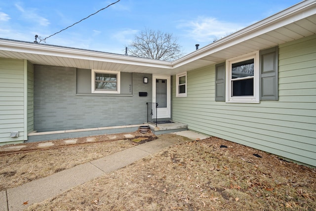 doorway to property with covered porch and brick siding