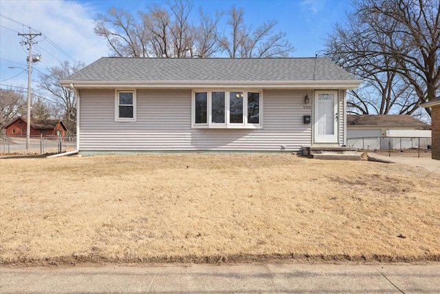 single story home with a shingled roof, fence, and a front lawn