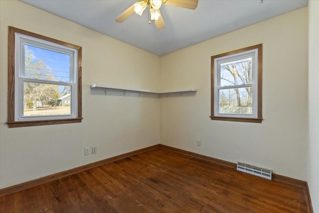 spare room featuring a wealth of natural light, visible vents, dark wood finished floors, and baseboards