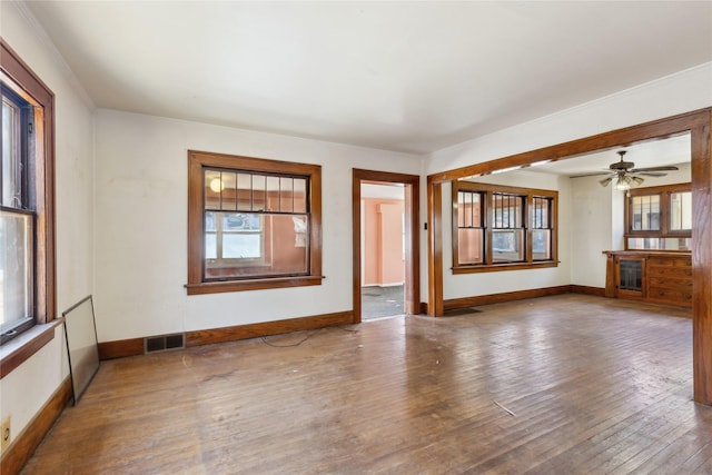 spare room with hardwood / wood-style floors, visible vents, and baseboards