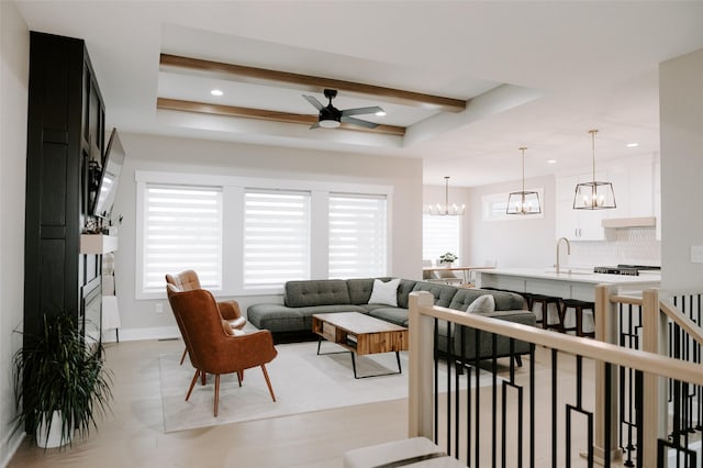 living area featuring a tray ceiling, beamed ceiling, recessed lighting, and ceiling fan with notable chandelier