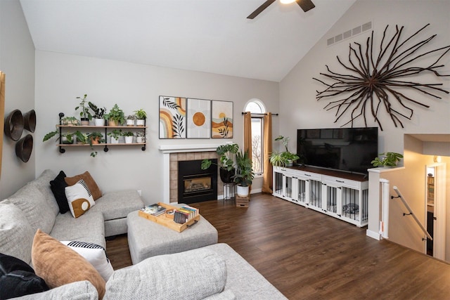 living area with visible vents, ceiling fan, wood finished floors, high vaulted ceiling, and a tile fireplace