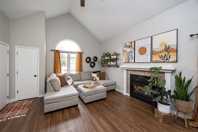 living area with a fireplace, ceiling fan, wood finished floors, high vaulted ceiling, and baseboards