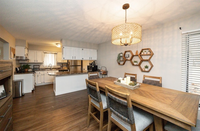 dining room with dark wood-type flooring, a chandelier, a textured ceiling, and baseboards