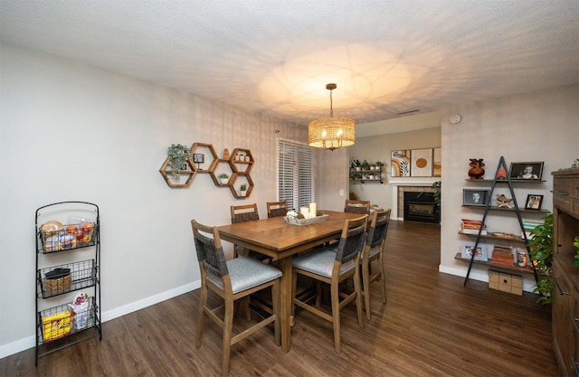 dining area with a tile fireplace, an inviting chandelier, baseboards, and wood finished floors