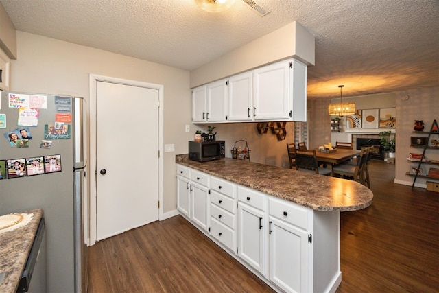 kitchen featuring dark wood-style floors, freestanding refrigerator, white cabinets, a textured ceiling, and a peninsula