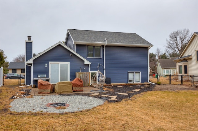 back of property with a gate, a chimney, fence, and a lawn