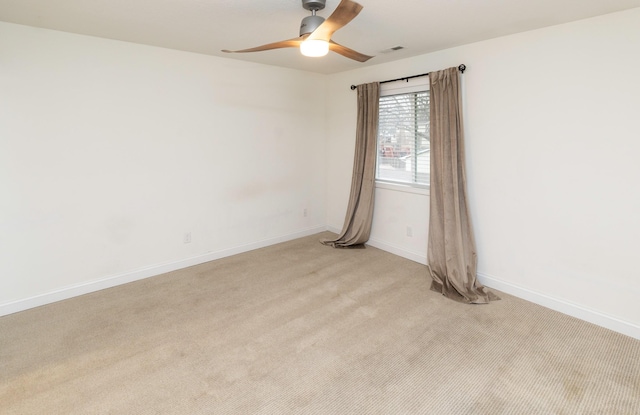 unfurnished room with baseboards, a ceiling fan, visible vents, and light colored carpet