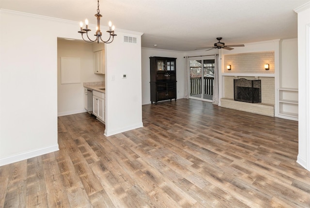 unfurnished living room with ceiling fan with notable chandelier, a fireplace, wood finished floors, visible vents, and ornamental molding