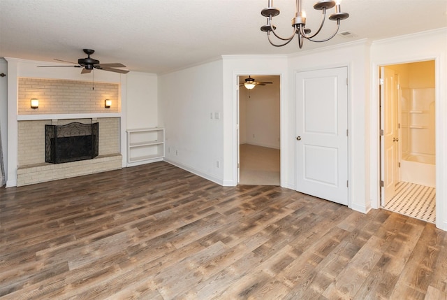 unfurnished living room with ceiling fan with notable chandelier, a fireplace, wood finished floors, visible vents, and crown molding