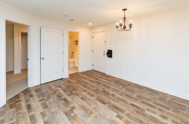 unfurnished room featuring baseboards, crown molding, a chandelier, and wood finished floors