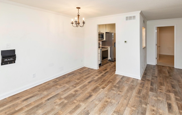 empty room with ornamental molding, visible vents, baseboards, and wood finished floors