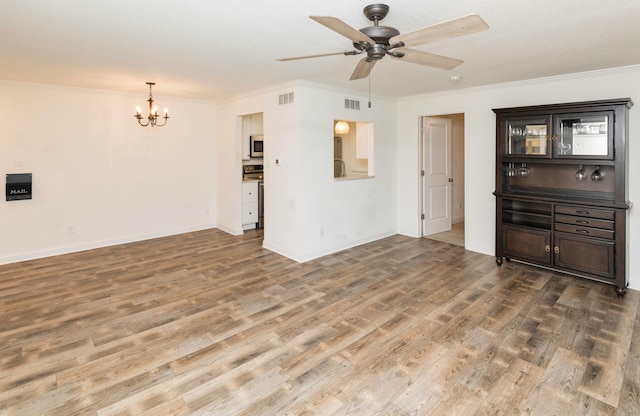 unfurnished living room featuring visible vents, crown molding, baseboards, and wood finished floors