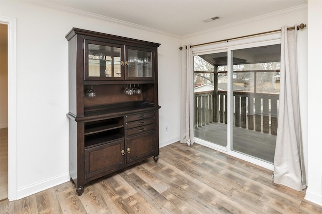 bar with baseboards, light wood-style flooring, visible vents, and crown molding