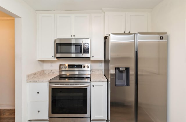 kitchen featuring baseboards, appliances with stainless steel finishes, light stone counters, and white cabinets