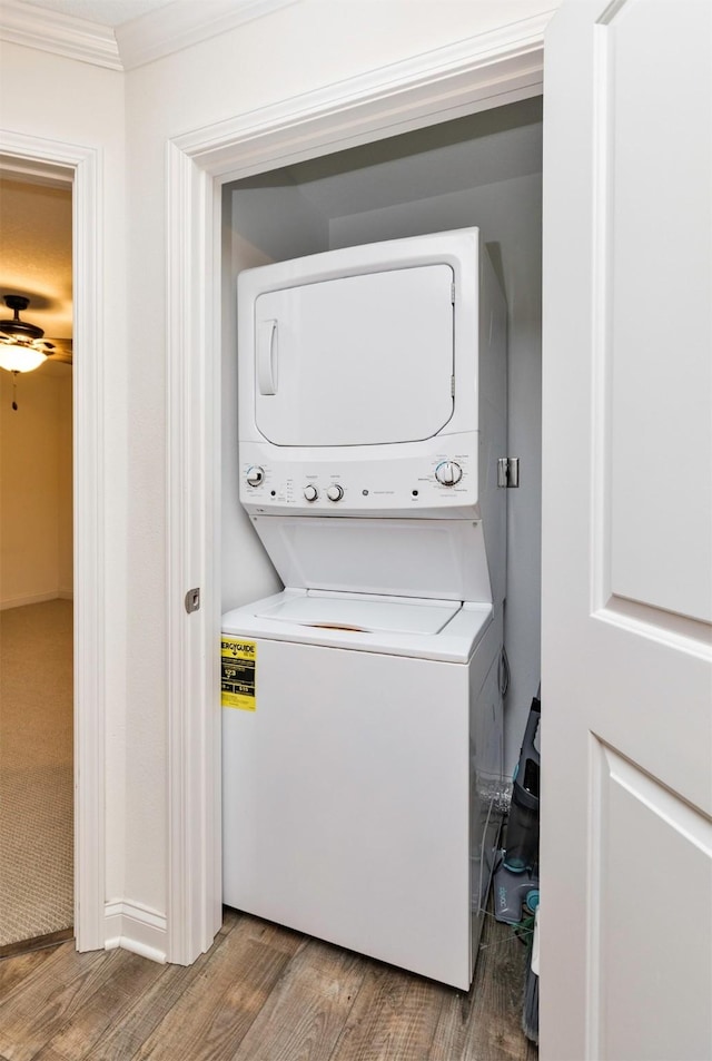 laundry room with stacked washer / dryer, laundry area, crown molding, and wood finished floors