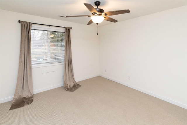 spare room featuring light carpet, a ceiling fan, and baseboards