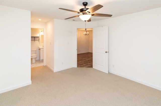 empty room featuring light carpet, baseboards, and ceiling fan with notable chandelier