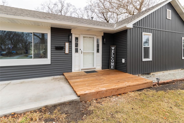 doorway to property featuring board and batten siding and roof with shingles