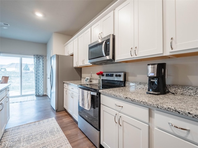 kitchen featuring stainless steel appliances, light wood-type flooring, white cabinets, and light stone counters