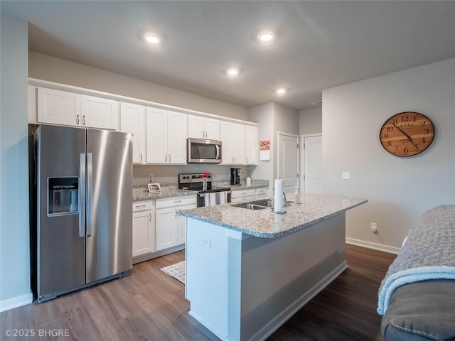 kitchen with appliances with stainless steel finishes, white cabinetry, an island with sink, and dark wood-style floors