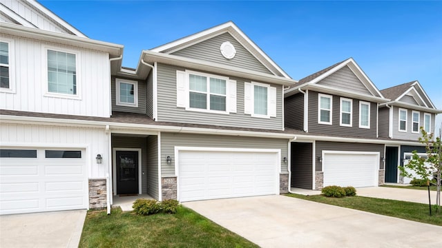 townhome / multi-family property featuring a garage, stone siding, and driveway