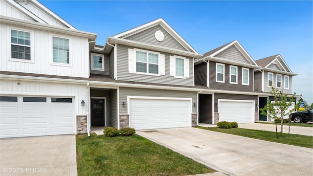 multi unit property featuring stone siding, an attached garage, and concrete driveway