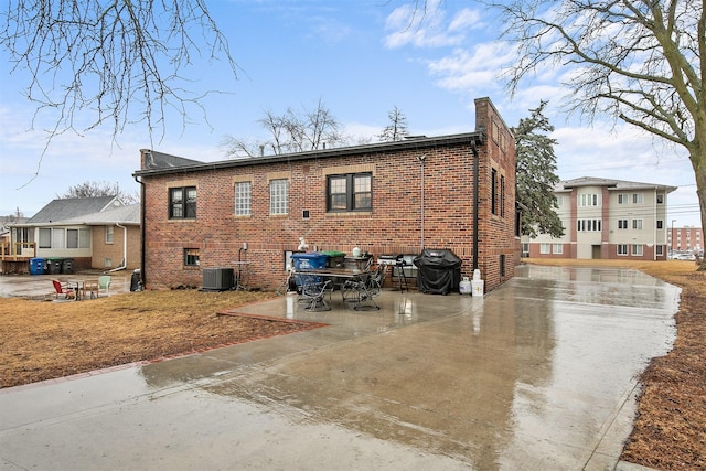 exterior space with a chimney, central AC, a patio, and brick siding