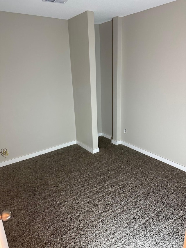 empty room with visible vents, baseboards, and dark colored carpet